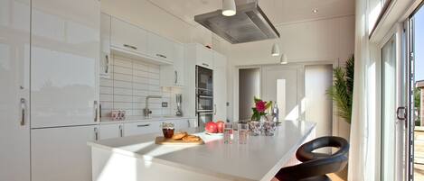A modern kitchen with white cabinetry, a central island, and a bar area with stools.