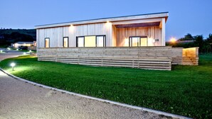 A modern building with a flat roof, large windows, and a wooden facade. - Batcombe Hollow, Strawberryfield Park (Cheddar)