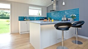 A modern kitchen with a large island, bar stools, and a view of the outdoors. - Batcombe Hollow, Strawberryfield Park (Cheddar)