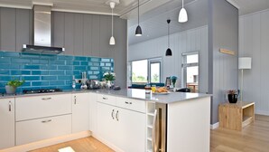 A modern kitchen with white cabinets, a blue backsplash, and a central island. - Batcombe Hollow, Strawberryfield Park (Cheddar)