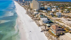 A coastal town with a long sandy beach, beachfront properties, and a prominent high-rise building. - Bourbon Breeze - Beachy Home Near the Gulf with Spacious Outdoor Pool Area (Miramar Beach)