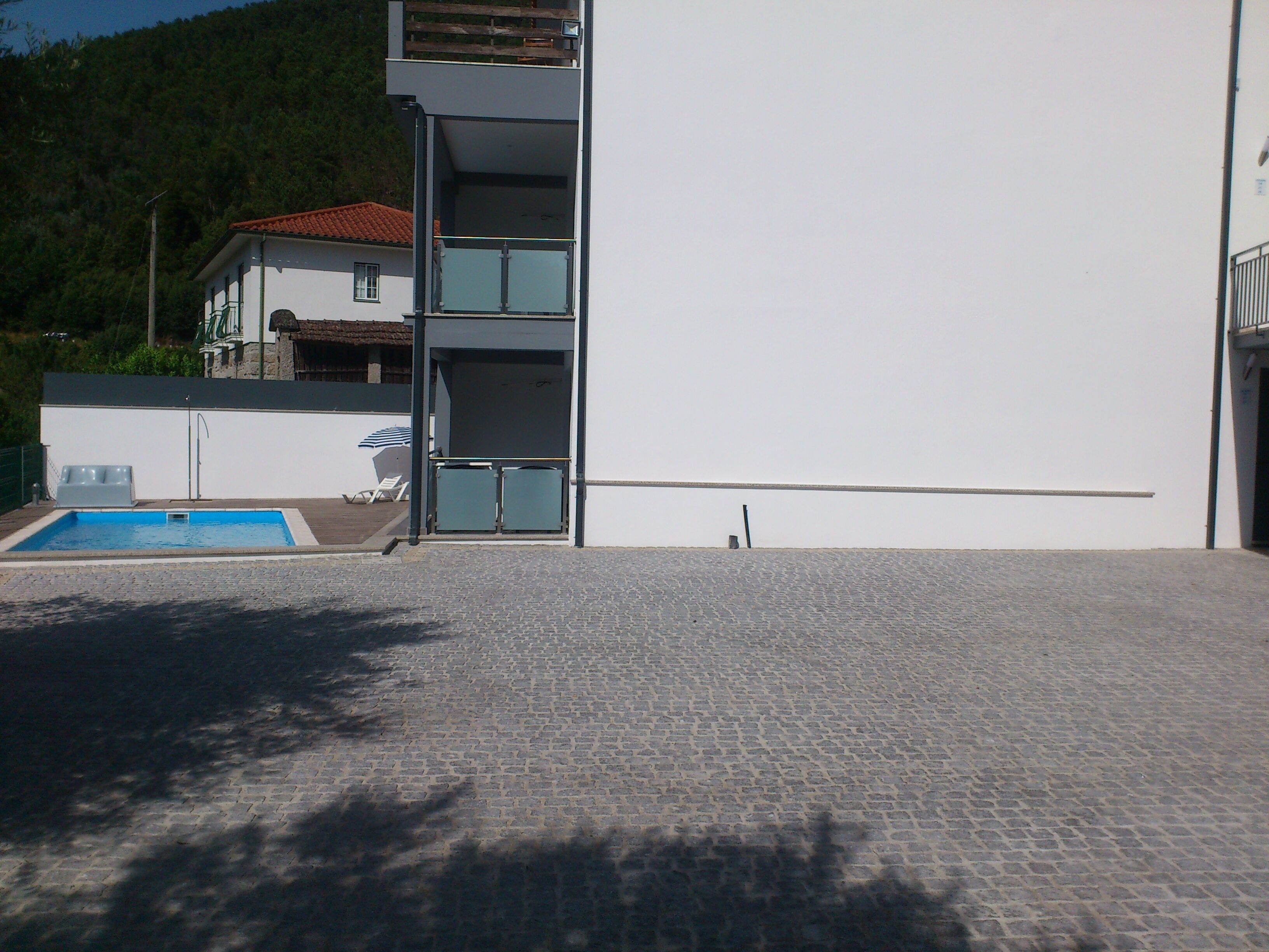 Un edificio moderno con piscina, balcón y escalera que lleva a un piso superior.