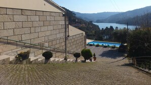 Gradians de pedra que condueixen a una zona de piscina amb vista a un llac i a les colines al fons.