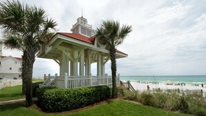 A gazebo with a red roof, surrounded by palm trees and a beach in the background. - Don't Worry Beach Happy - Lakefront Vacation Home Near the Beach with a Private Pool (Miramar Beach)