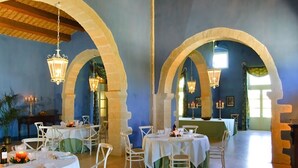 A dining area with white tables and chairs, archways, hanging lanterns, and a blue wall. - ANTICO FEUDO SICILIANO (Syracuse)