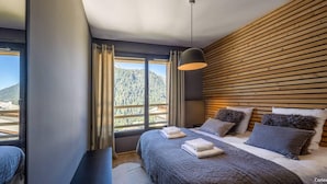 Una moderna camera d'hotel con un ampio letto, una parete con listelli di legno e vista su un paesaggio montuoso.