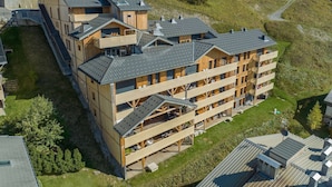 Un edificio in legno su più piani con balconi, immerso in un paesaggio erboso e alberato.
