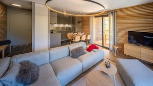 Un soggiorno moderno con un divano angolare grigio, un tavolino rotondo e una televisione su un mobile in legno.