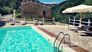 A swimming pool with clear water, a stone building, and a white fence. - Brisighella Green Wellness (Brisighella)