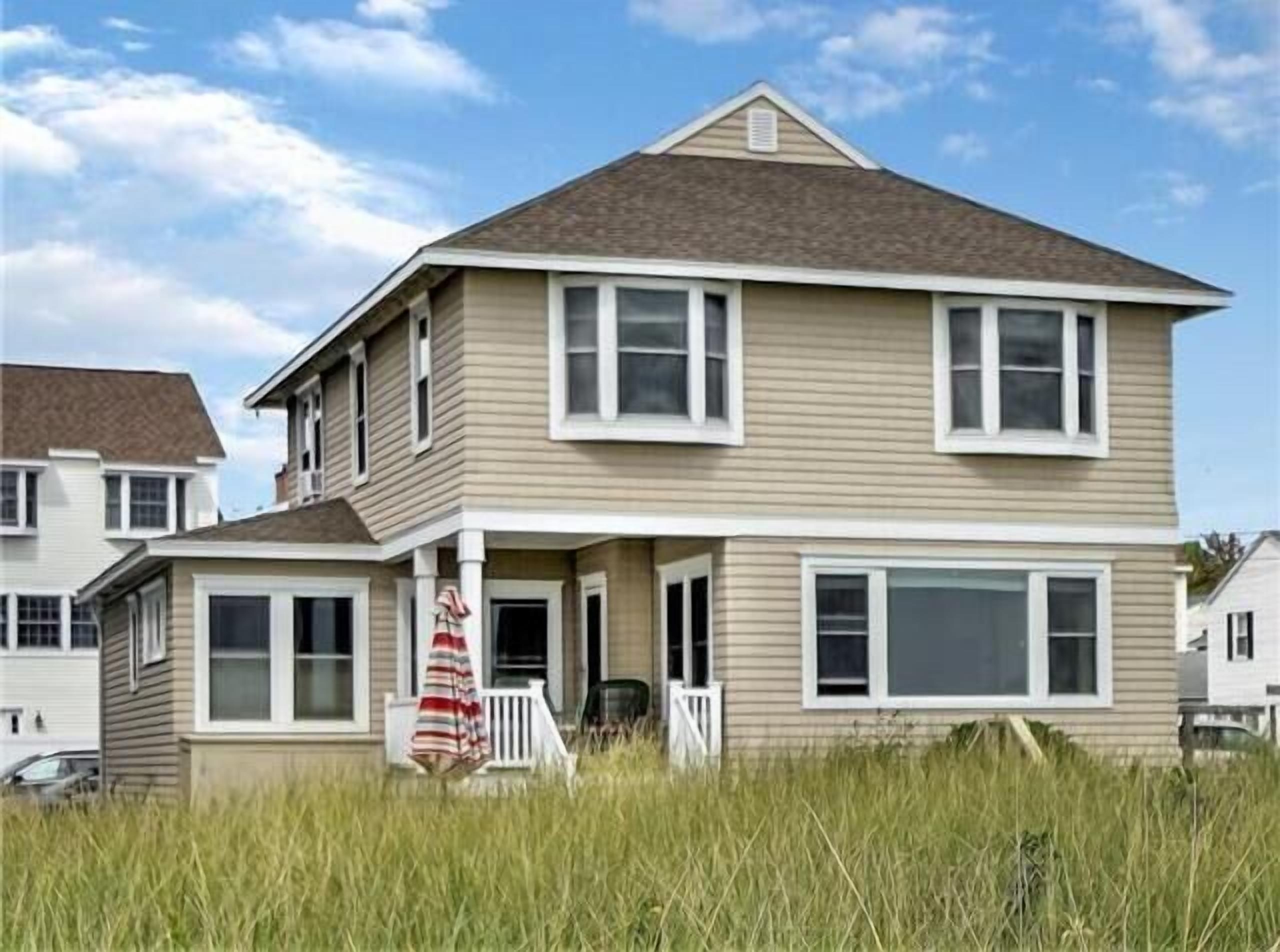 A two-story house with a front porch, a garage, and a large window on the second floor.
