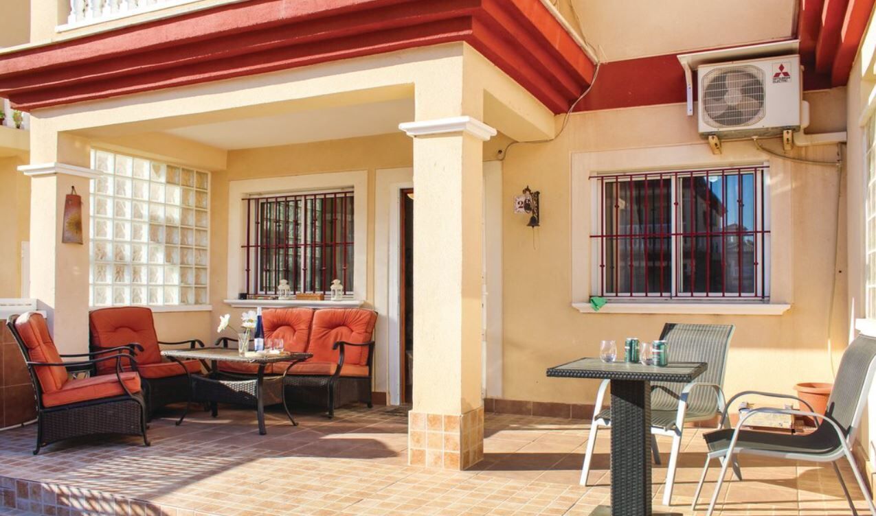 Une terrasse extérieure aménagée avec des meubles en osier, une table et des chaises.