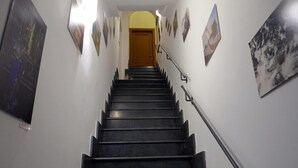 Uma escadaria com degraus e corrimãos pretos, que leva a uma porta no topo.
