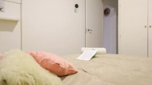 A bedroom with a bed, pillows, and a door.