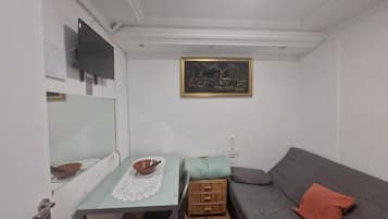 Una habitación pequeña con una mesa, un sofá, un televisor y un cuadro en la pared.