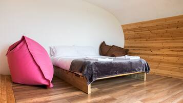 A bed with a wooden frame, a pink bean bag, and a brown pillow.