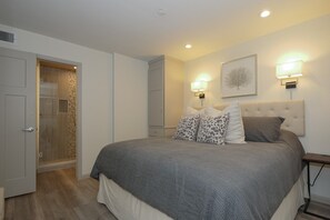 A bedroom with a large bed, a wardrobe, a walk-in closet, and a shower area. - Great Ocean views, Oceanfront Heated Pool! (Hilton Head)