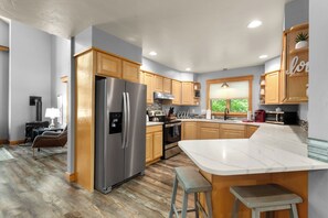 A modern kitchen with wooden cabinets, stainless steel appliances, and a marble countertop. - Townhome perfectly located between downtown, Ski resort and Whitefish Lake!!! AC just installed. (Whitefish)