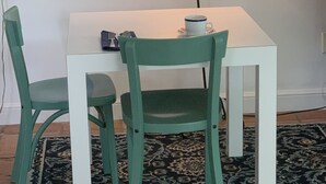 A small dining area with a white table and two green chairs, a white lamp, and a cup on the table. - Zen Garden Private Guest House by Beach n Golf (Naples)