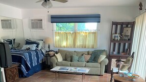 A living room with a sofa, a coffee table, and a television. - Zen Garden Private Guest House by Beach n Golf (Naples)
