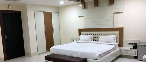 A modern bedroom with a large bed, a bedside table, a nightstand, and a built-in bench.