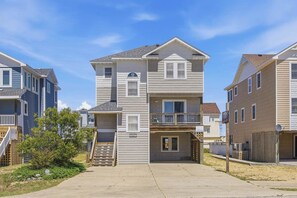 A multi-story residential building with a front porch, a garage, and a small outdoor area with a wooden deck.