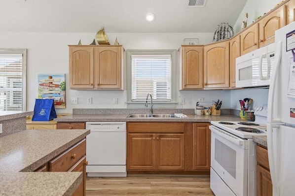 A kitchen with wooden cabinets, a dishwasher, a stove, and a microwave.