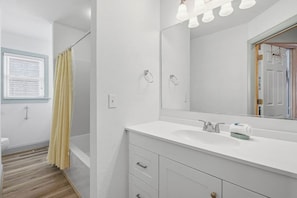 A bathroom with a white sink, mirror, and shower curtain.