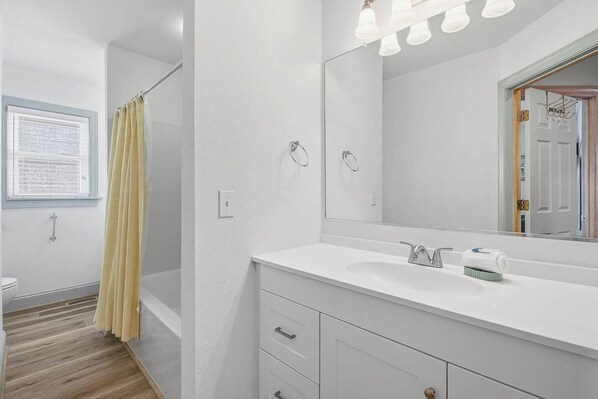 Une salle de bain avec un lavabo blanc, un miroir et un rideau de douche.