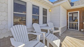 Une terrasse couverte, dotée de chaises Adirondack et d’une rambarde en bois.