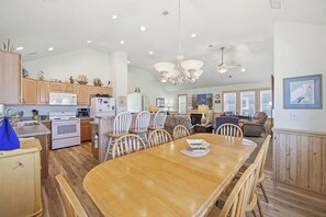 A spacious kitchen with wooden cabinets, a dining area with a large wooden table, and a living area with a sofa and chairs.