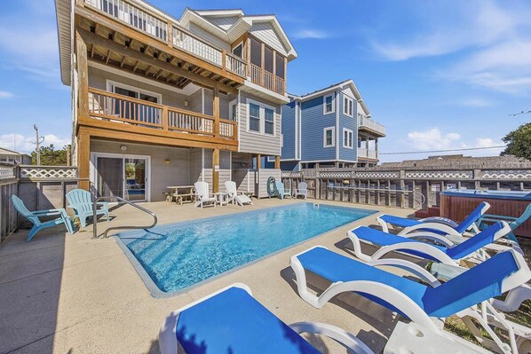 A pool area with lounge chairs and a building with multiple balconies.