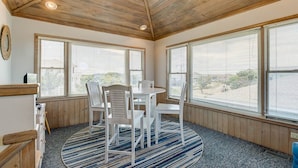 A room with a wooden ceiling, large windows, a round table with chairs, and a striped rug. - Dancing Dolphin | 240 ft from the beach | Private Pool, Hot Tub, Dog Friendly | Duck (Duck)