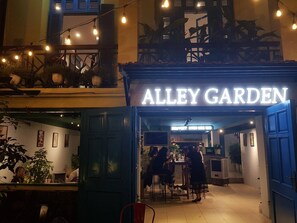L'esterno di Alley Garden, un ristorante con posti a sedere all'aperto e luci decorative.
