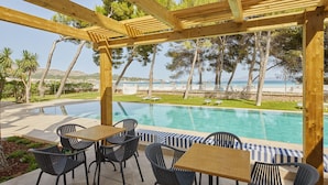 Un espace extérieur avec piscine, agrémenté d’une pergola en bois, de chaises longues et de tables.