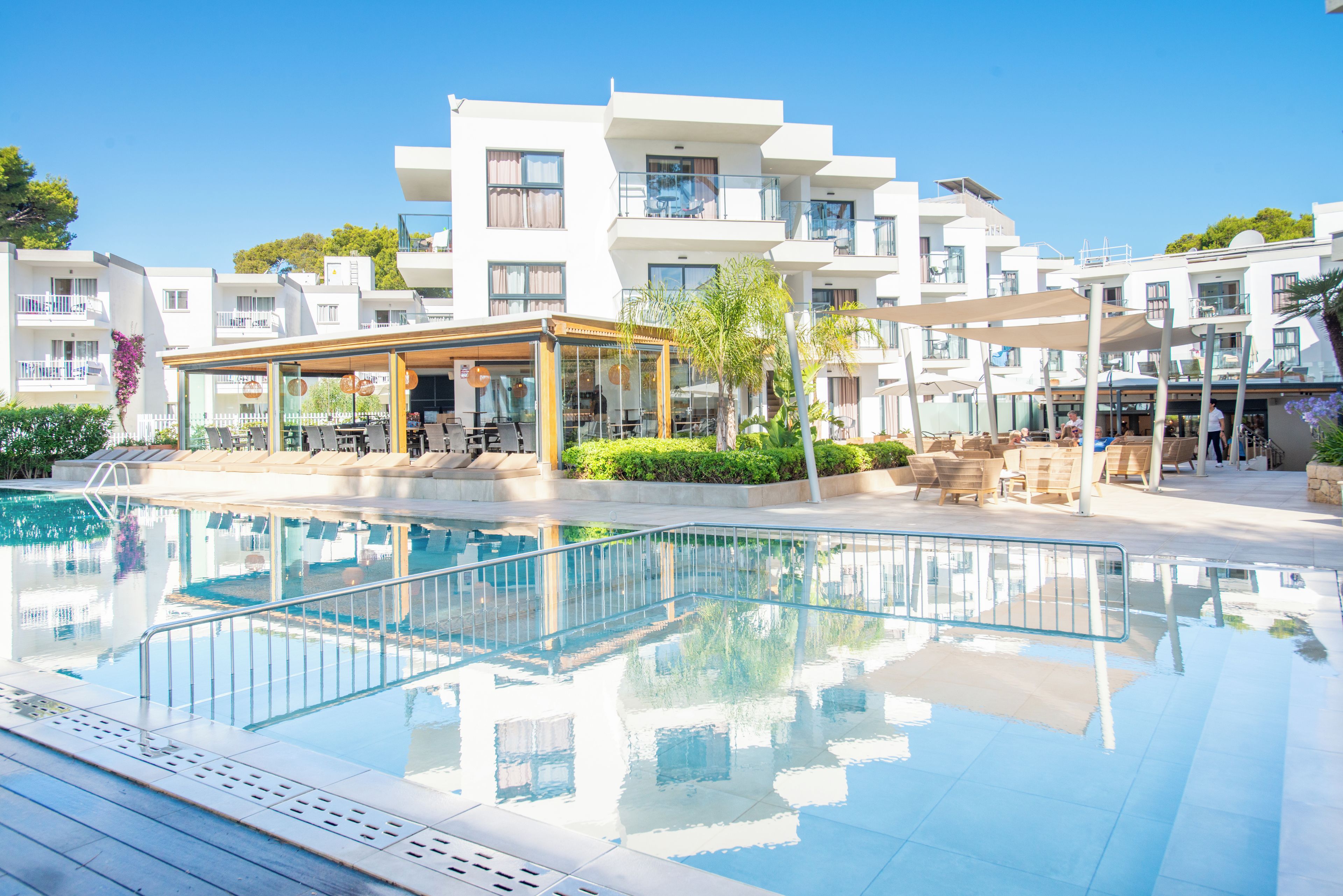 A modern hotel with a swimming pool, outdoor seating, and a covered patio area.
