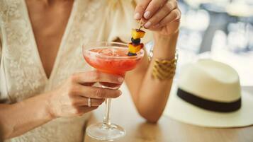 A person holding a cocktail glass with a fruit skewer.