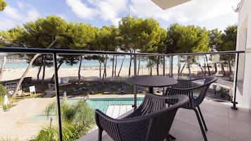 A balcony with a pool, chairs, and a view of the beach.