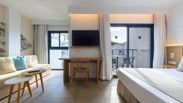 Una habitación de hotel moderna con cama, escritorio con televisor, una mesita pequeña y un sofá.