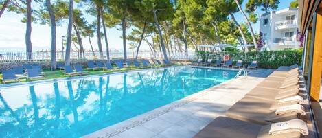 Un espace aménagé au bord de la piscine, avec des chaises longues et une vue dégagée sur la mer.