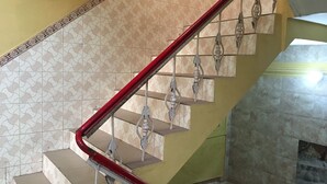 Una escalera con barandillas de metal ornamentadas y baldosas de pared estampadas.