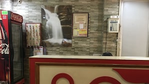 Zona de recepción con máquina expendedora de Coca-Cola, un mural de cascada y un tablón de anuncios con un letrero de 'CHECK OUT'.