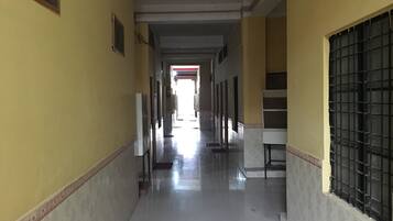 A long, narrow hallway with tiled walls and a shiny floor, leading to a bright exit.