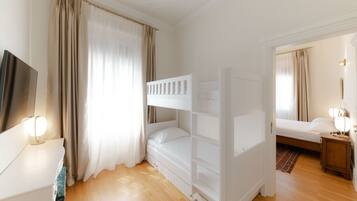A room with a bunk bed, a bedside table with a lamp, a wardrobe, and a mirror.