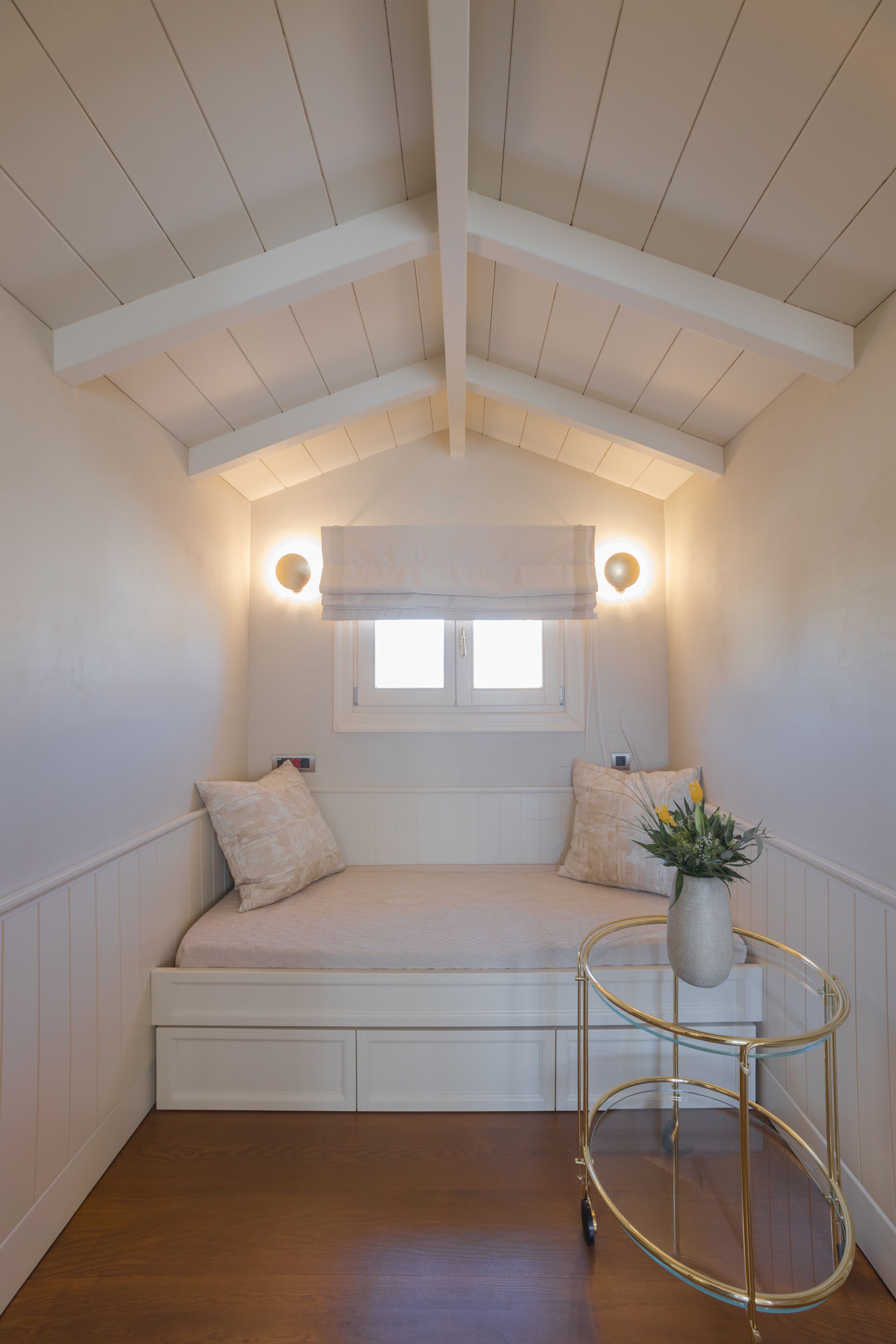 A cozy room with a built-in bench, a small window, and a wall-mounted light fixture.