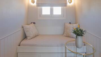 A cozy room with a built-in bench, a small window, and a wall-mounted light fixture.
