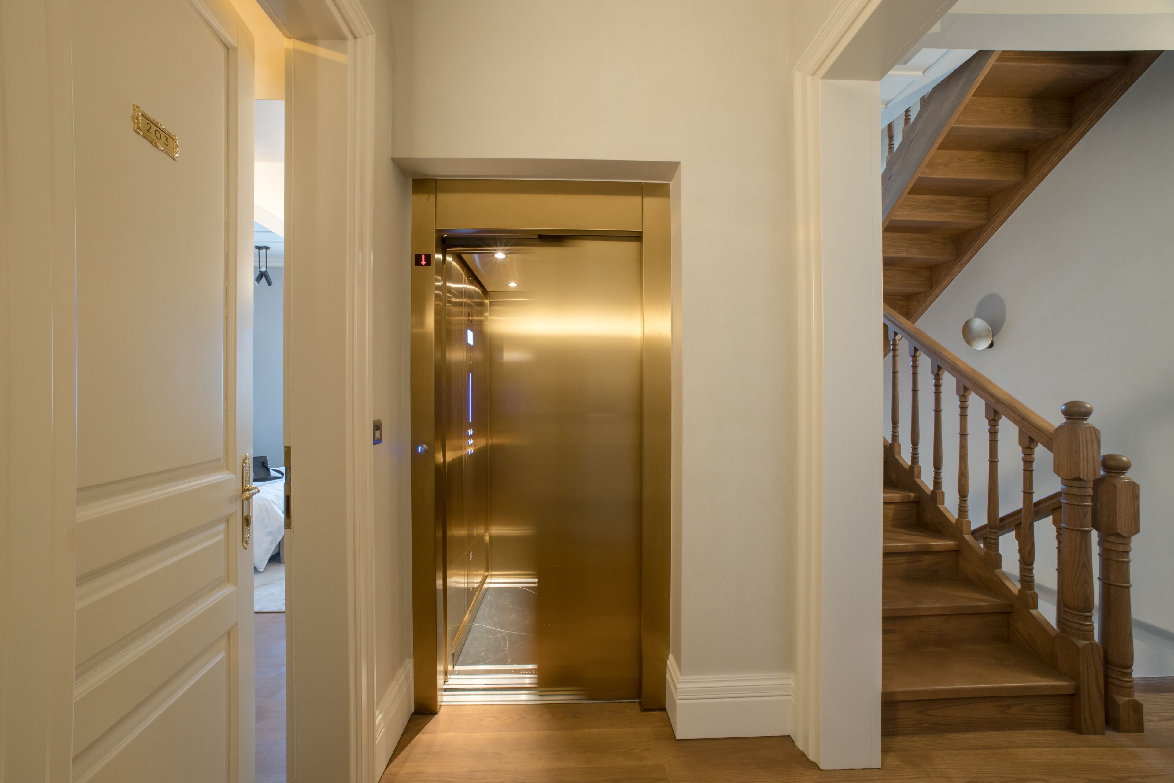 A hallway with a closed elevator and a wooden staircase.