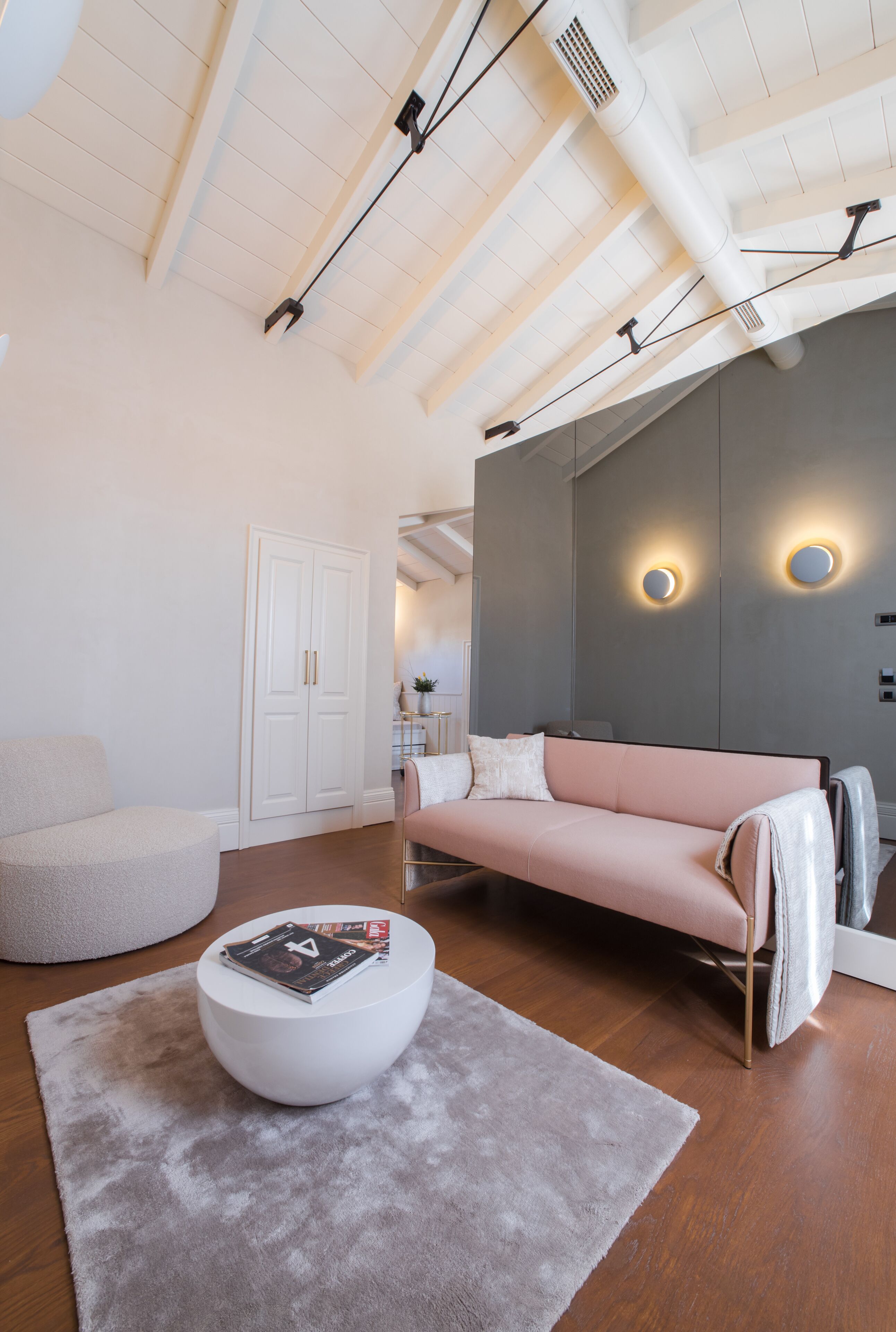 Una sala moderna con una mesa redonda, un sofá rosa y un sillón blanco.