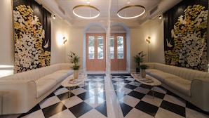 Eine Lobby mit Schachbrettmuster, zwei Sofas, einer zentralen Tür und Wandbildern.