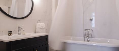 A modern bathroom with a freestanding bathtub, a vanity with a mirror, and a shower curtain.