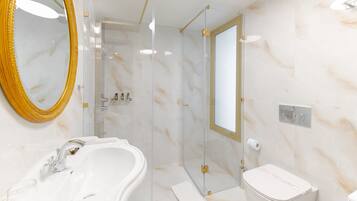 A modern bathroom with a marble sink, a toilet, and a glass-enclosed shower.